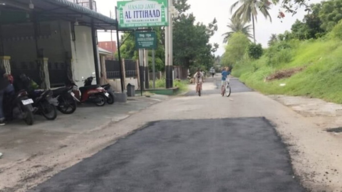 Petugas Dinas PUPR Kota Padang sedang melakukan penambalan jalan berlubang untuk meningkatkan keamanan pengguna jalan.